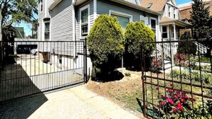 Una casa de dos pisos con patio frontal, entrada con portón y antena parabólica.