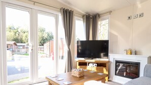Ein Wohnzimmer mit Fernseher, Kamin und Blick ins Freie.