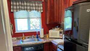 Una cocina con armarios de madera, un refrigerador negro, un microondas y un lavavajillas.