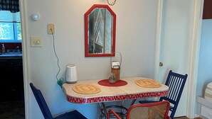 Un comedor con una mesa, sillas, un espejo y una lámpara en el techo.