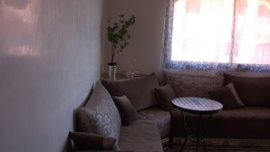 A cozy living room with a sofa, a small round table, and a potted plant.