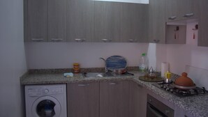 A compact kitchen with a washing machine, sink, and stove.