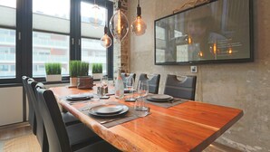 A dining area with a wooden table, black chairs, hanging light fixtures, and a framed picture on the wall. - Luxury Loft Sylt - your special vacation home (Westerland)