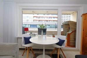 Relax in this inviting space with a large window offering a view of the city, a comfortable sofa, and a round table for two.