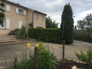Un immeuble résidentiel doté d’un toit en tuiles, d’une allée pavée et d’un jardin bien entretenu, agrémenté de fleurs et d’arbustes.
