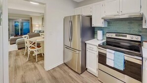 A modern kitchen with stainless steel appliances, white cabinets, and a tiled backsplash. - 5 Min to Beach, Renovated Townhome (Mount Pleasant)