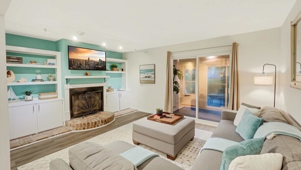 A modern living room with a fireplace, a large sofa, and a sliding glass door leading to a balcony. - 5 Min to Beach, Renovated Townhome (Mount Pleasant)