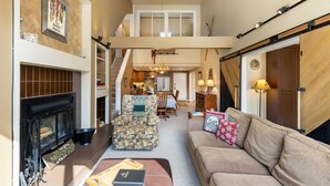A spacious living room with a fireplace, a patterned armchair, a sofa, and a dining area in the background. - Beautiful Condo in the Pines, Mountain Views, Shared Pool & Hot Tub (Keystone)