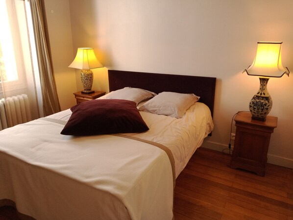 A neatly made bed with white and brown bedding, two bedside lamps, and a wooden floor. - Château du Breuil (Beaulieu-sur-Layon)