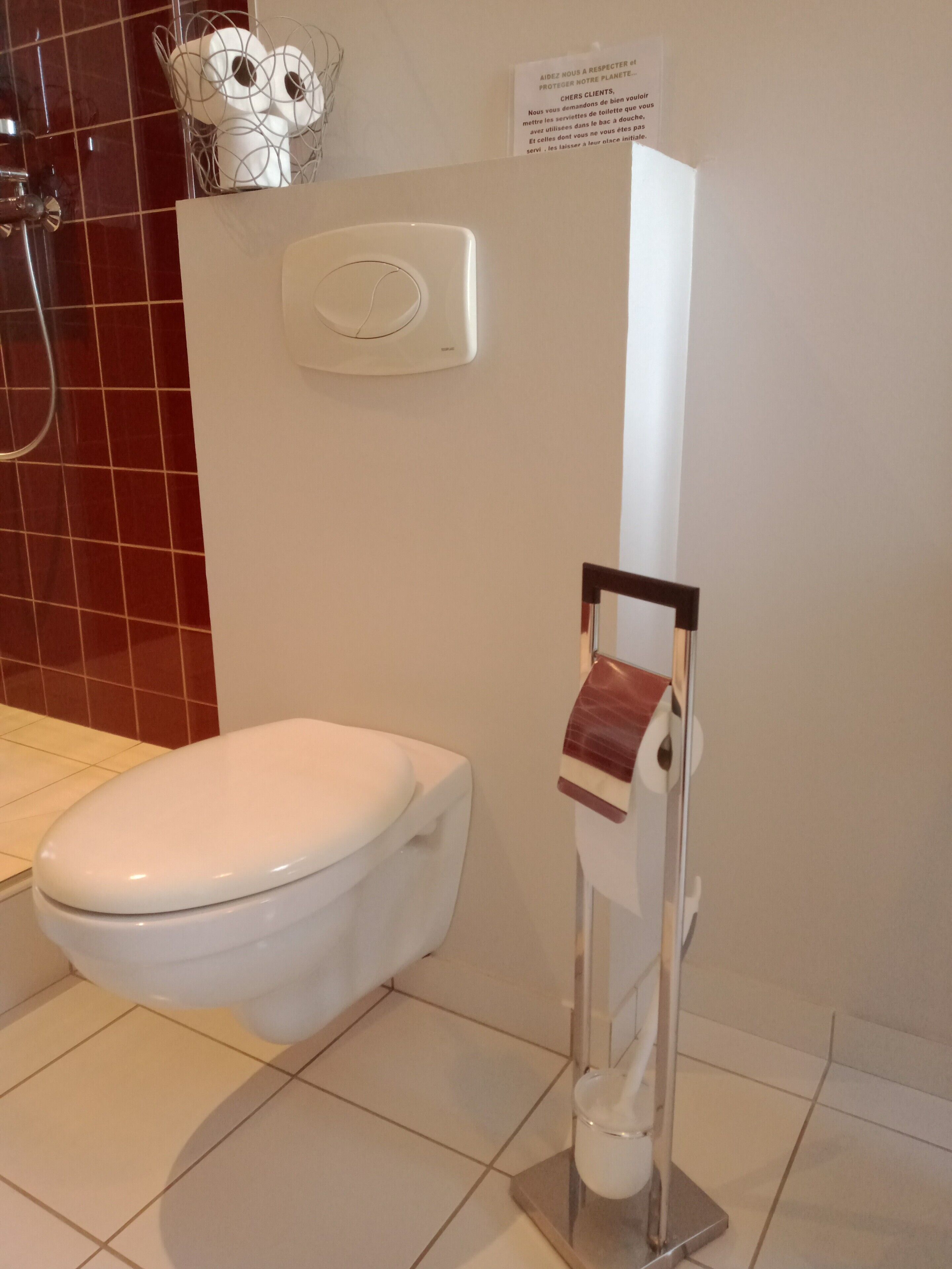 Un baño con un inodoro blanco, un dispensador de toallas de papel y un secador de manos.