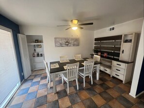 Une cuisine de taille réduite comprenant une table à manger, des chaises, un ventilateur de plafond et un réfrigérateur.