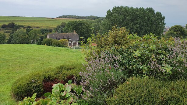 Ein ländliches Haus, umgeben von üppiger Vegetation und Feldern.