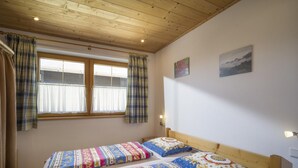 A room with two beds, wooden ceiling, a window with curtains, and wall-mounted lights. - Apartment 1 minute from the ski lift (Brixen im Thale)