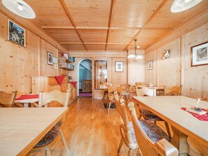 A wooden interior with a long dining table, multiple chairs, and a staircase leading to an upper level. - Holiday home near ski lift (Kirchberg in Tirol)