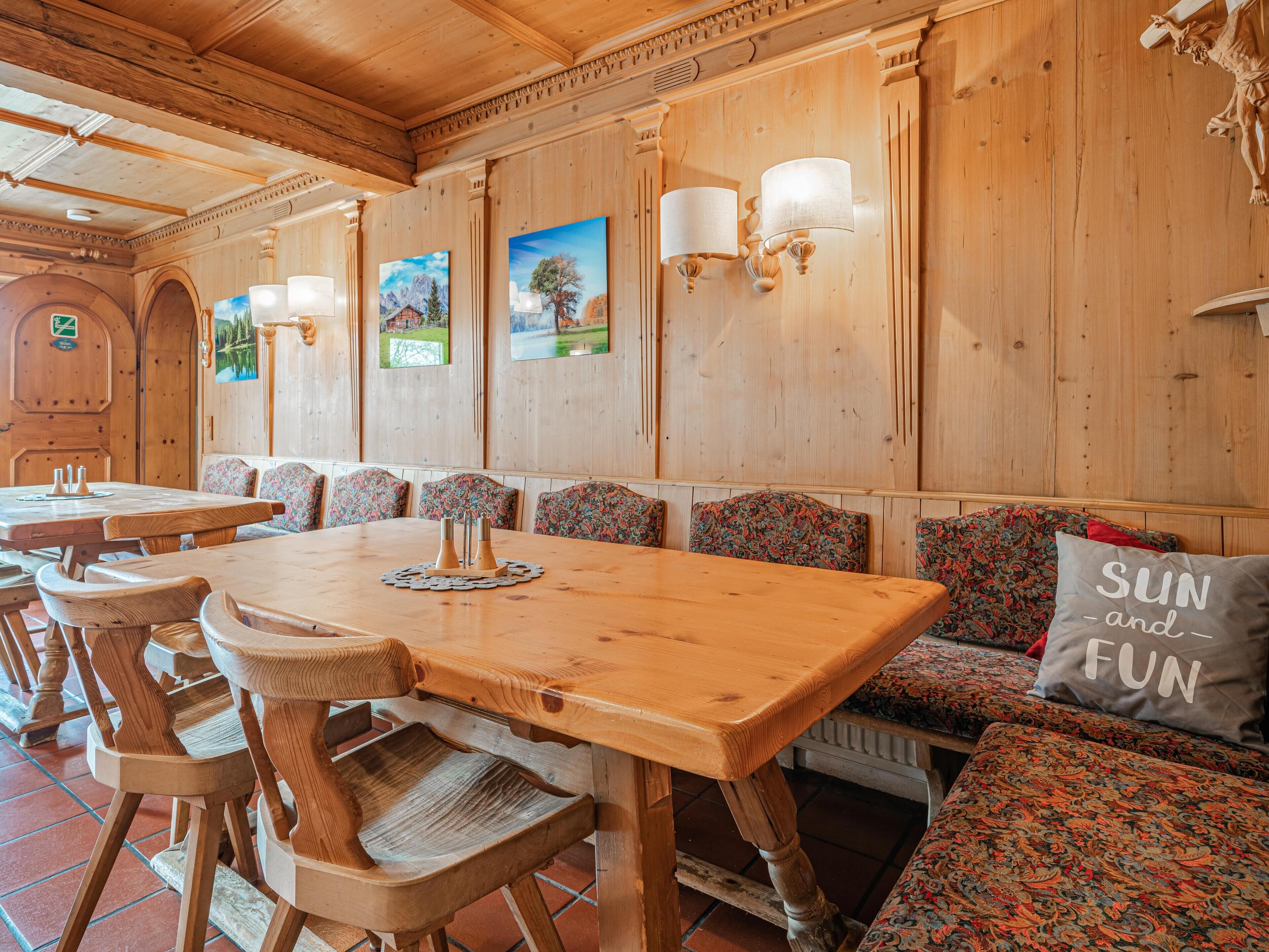 Un intérieur en bois avec une longue table à manger, des bancs et des lampes fixées au mur.