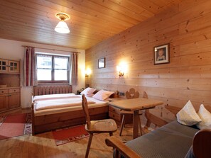 A wooden cabin room with a bed, a table, and a chair. - Holiday home near ski lift (Kirchberg in Tirol)