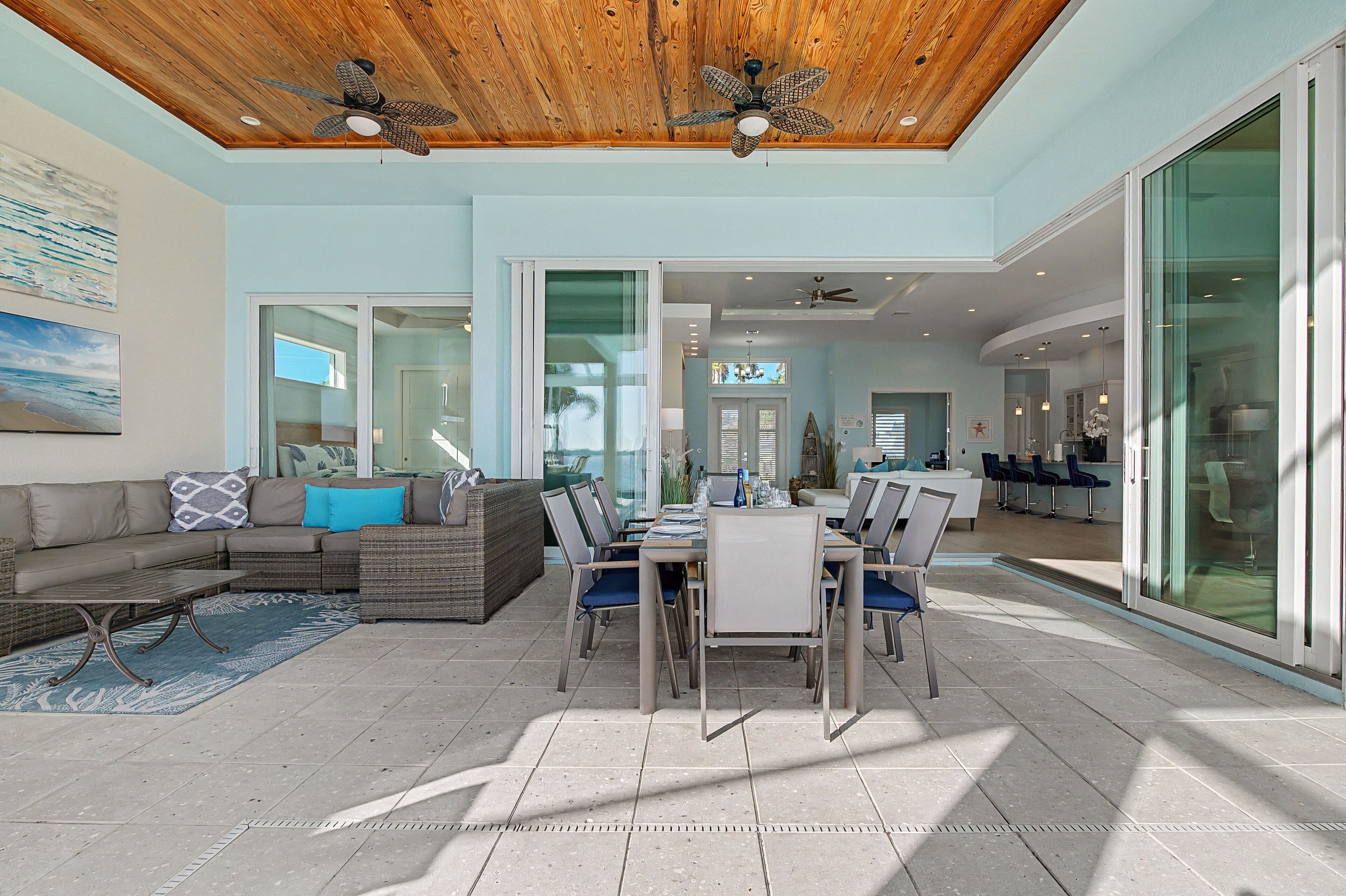 A spacious living area with a dining table, sofas, and a ceiling fan.