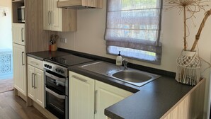 Uma cozinha moderna com armários brancos, bancada preta, pia de aço inoxidável e forno embutido.