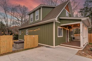 A two-story house with a porch, a hot tub, and a deck.
