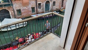 Un balcon donnant sur un canal, avec une gondole et un bateau amarré à proximité.