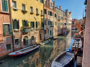 A narrow canal with boats docked along the sides, surrounded by historic buildings with balconies and shutters.