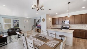 A spacious living area with a dining table, sofa, and kitchen with wooden cabinets and a microwave.
