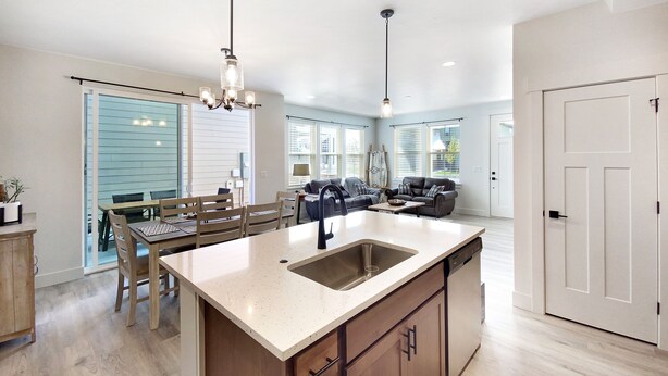 A spacious kitchen with a large island, wooden cabinets, and a dining area with a table and chairs.