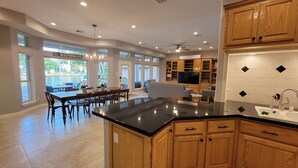 A spacious kitchen with wooden cabinets, a black countertop, and a dining area with a table and chairs.