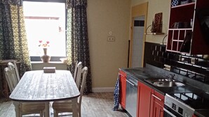 A kitchen with a dining table, chairs, and a red and black stove. - New apartment at the market place Lieser Moseloefer 30 meters (Lieser)