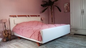 A bedroom with a bed, a nightstand, a lamp, a wardrobe, and a large plant. - New apartment at the market place Lieser Moseloefer 30 meters (Lieser)