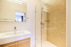 Une salle de bain moderne avec une douche à parois de verre, un lavabo blanc et un meuble-lavabo en bois.