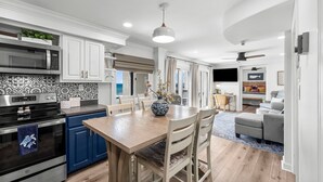 Een moderne keuken met witte kasten, een zwart fornuis en een blauw aanrecht.