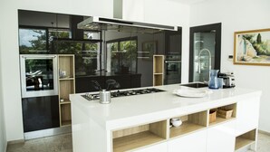 A modern kitchen with a central island, stainless steel appliances, and a large window. - Villa Bonheur Villa Exceptionnelle la Soukra (La Soukra)