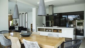 A modern kitchen with white cabinetry, a central island, and pendant lighting. - Villa Bonheur Villa Exceptionnelle la Soukra (La Soukra)