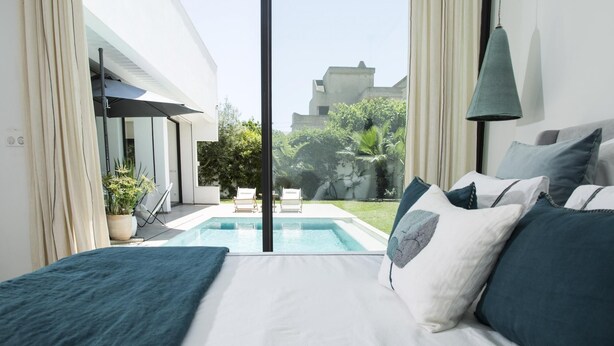 A modern bedroom with a large bed, a view of a swimming pool, and a balcony. - Villa Bonheur Villa Exceptionnelle la Soukra (La Soukra)