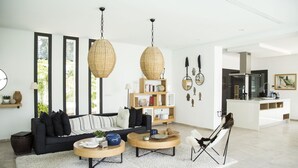 A modern living room with a black sofa, two round wooden coffee tables, and a white shag rug. - Villa Bonheur Villa Exceptionnelle la Soukra (La Soukra)