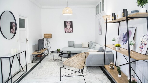 A modern living room with a grey sofa, a wicker chair, a coffee table, and a TV. There are framed pictures on the wall, a bookshelf, and a potted plant. - Apt Moderne Face au Parc et au c ur de la Marsa (La Marsa)