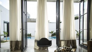A room with a glass table, a black chair, and a patterned pillow. - Les Verrières De Gammarth: Villa moderne +Piscine (La Marsa)