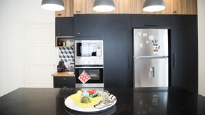 A modern kitchen with a central island, a built-in oven, a microwave, and a stainless steel refrigerator. - Les Verrières De Gammarth: Villa moderne +Piscine (La Marsa)