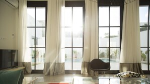 A modern living room with a large window, a flat-screen TV, a glass coffee table, and a comfortable seating area. - Les Verrières De Gammarth: Villa moderne +Piscine (La Marsa)