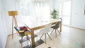 Ein stilvoller Essbereich mit Holztisch, zwei Stühlen, einer Stehlampe und einem Blumentopf.