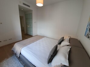 Un dormitorio con cama, almohadas, una alfombra y un cuadro en la pared.