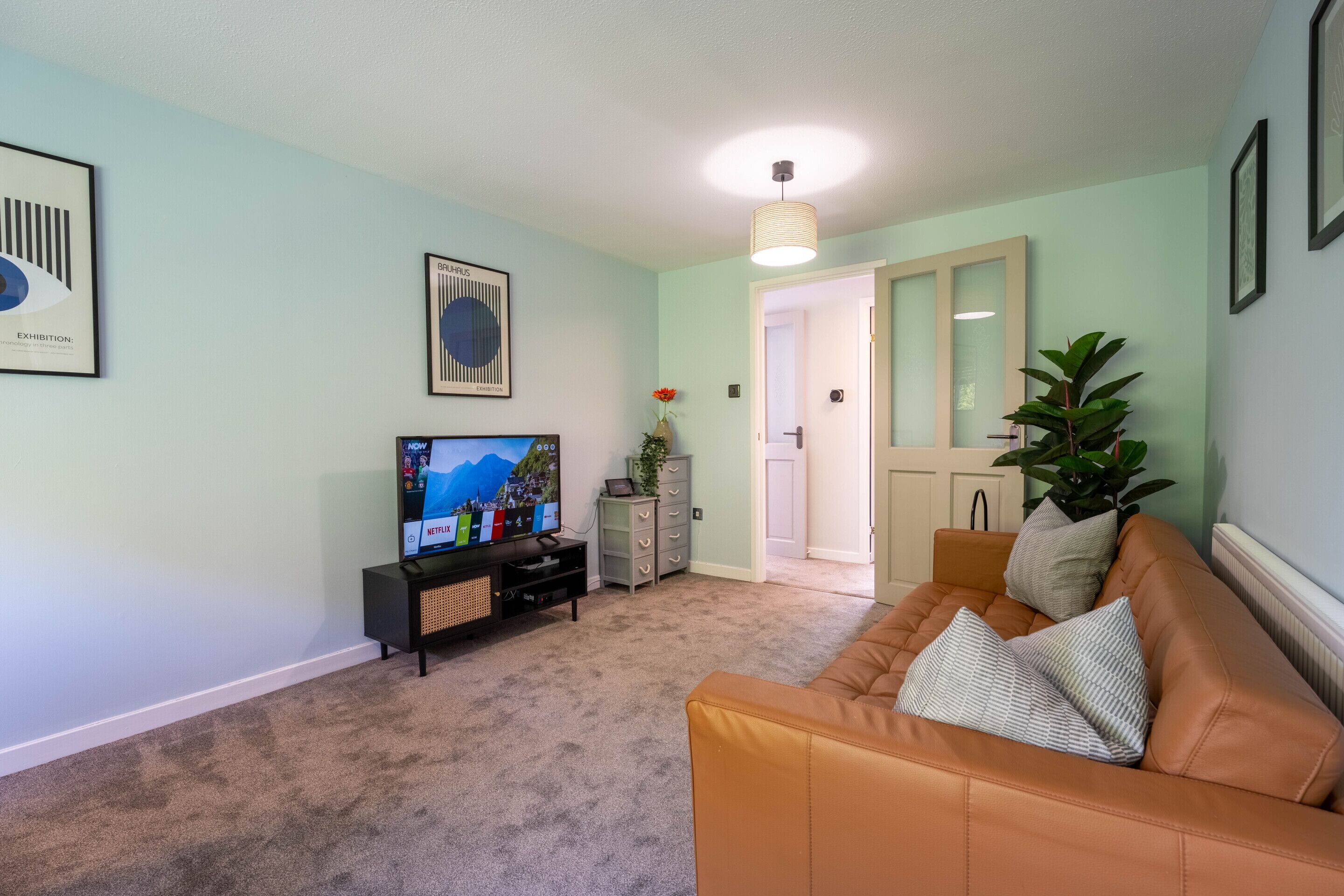 A living room with a TV, a sofa, a cabinet, and a door leading to another room.