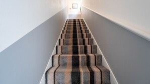 Una escalera con alfombra a rayas que lleva a una puerta al final.