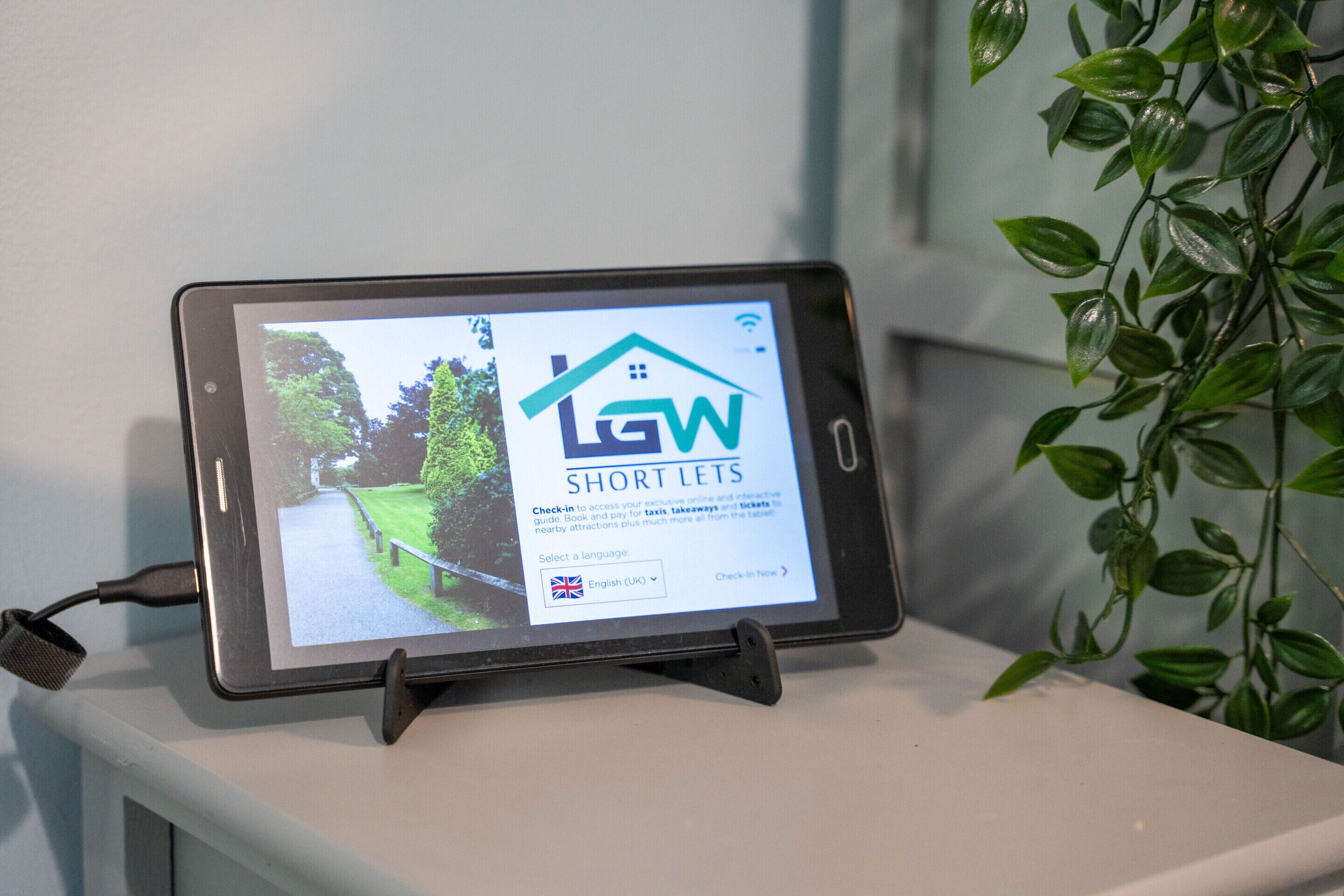 Un tablet su un supporto mostra un annuncio immobiliare per 'Short Lets' con vista sul giardino.