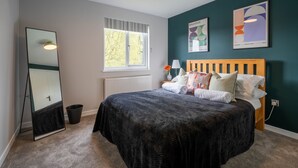 Un dormitorio con cama, un espejo grande, una ventana y obras de arte en la pared.