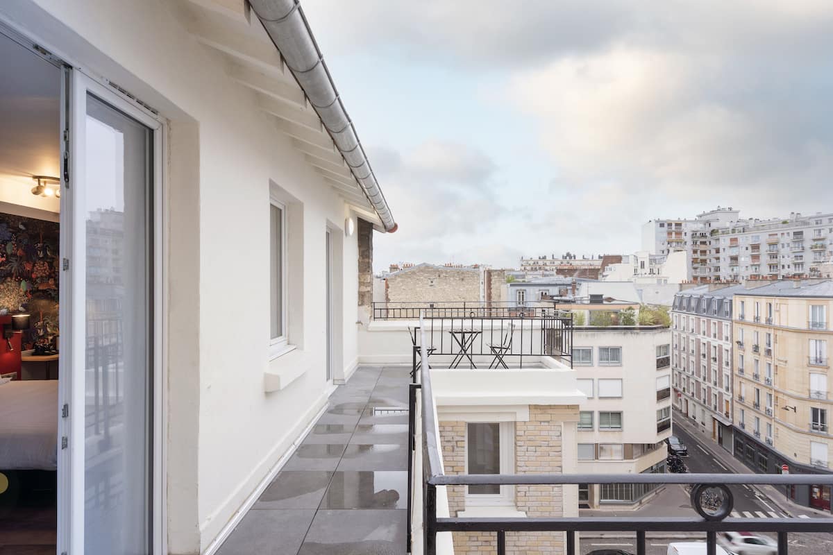 A balcony with a view of a cityscape, featuring modern buildings and a clear sky.