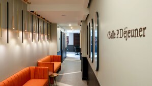 Un moderno vestíbulo de hotel con asientos anaranjados, un largo pasillo y un cartel que dice 