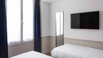 Un dormitorio con dos camas, un ventanal con cortinas, un espejo y un televisor de pantalla plana en la pared.