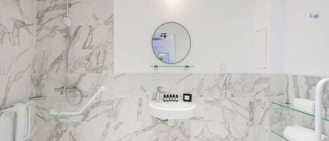A modern bathroom with a marble wall, a round mirror, a sink, and a glass shelf.